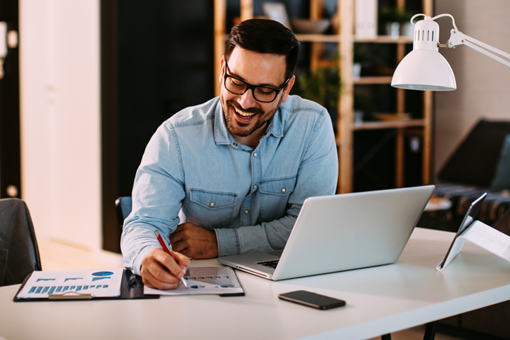 Financial Solutions | Business Man working on laptop while writing notes